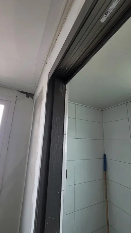 블랙 프레임 측면과 레일 단면, 안쪽으로 타일 벽이 보임