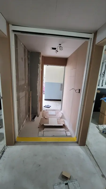 합판 마감된 벽체 사이로 복도 끝이 보이는 개구부